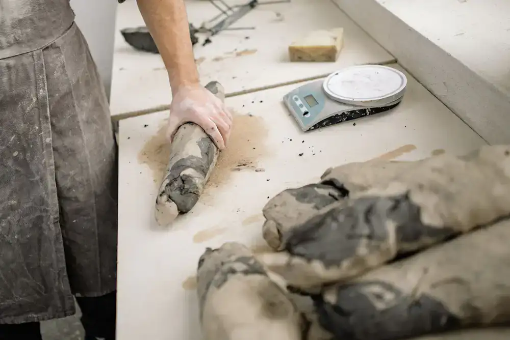 Hands carefully shaping raw clay in the studio