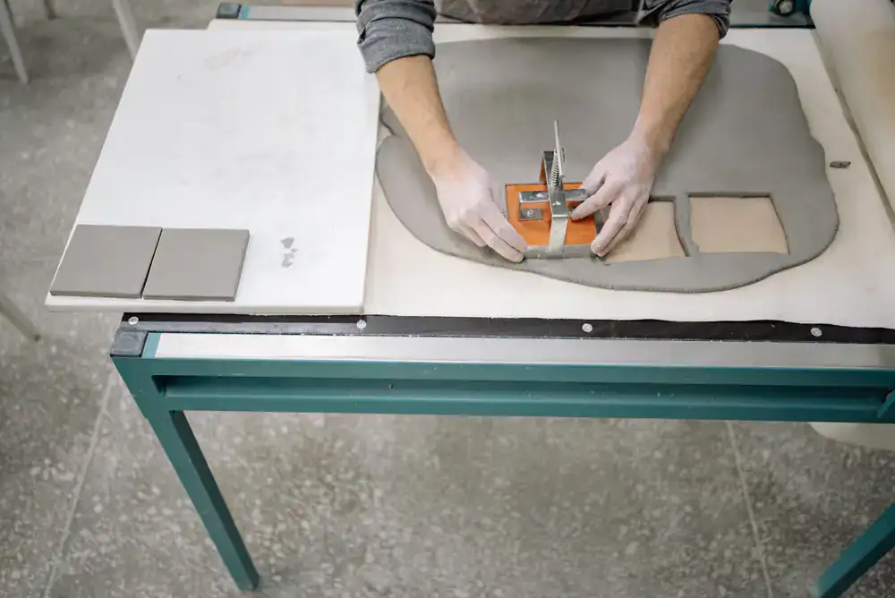 Artisan hands shaping and glazing a clay tile
